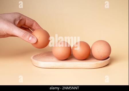 Faire prendre à la main un œuf de poulet sain dans la coquille du plateau en bois Photo de haute qualité Banque D'Images