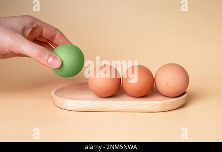 À la main prenant peint teint en œuf vert pour Pâques, en choisissant parmi les œufs de poulet non cuits en coquille du plateau en bois Photo de haute qualité Banque D'Images