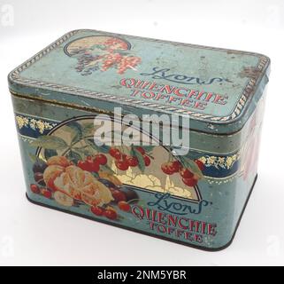 Lyons Toffee Tin des années 1920 Belle illustration en dehors de divers fruits. Illustration intérieure d'enfants construisant un grand château de sable, avec la mer en arrière-plan, des seaux et des pique, et drapeau union jack sur le dessus. Impression lithographique. Lyons était une célèbre marque d'épicerie au détail. Emballage vintage. Banque D'Images