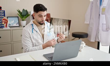 Jeune homme arabe médecin regardant la radiographie ayant appel vidéo à la clinique Banque D'Images