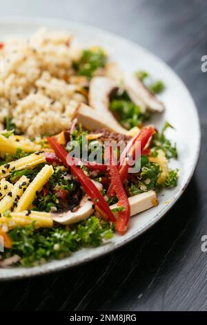 Salade de kale asiatique faite maison avec quinoa, carottes, haricots fava, poivron, maïs pour bébé, champignons et tofu fumé Banque D'Images