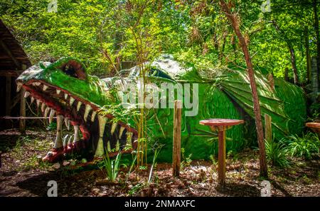 Dragon vert squameux dans un parc boisé où les enfants peuvent jouer à l'intérieur Banque D'Images