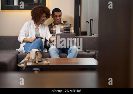 Couple multiracial assis sur un canapé devant un ordinateur portable Banque D'Images