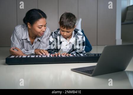 Maman enseigne à l'adolescent à jouer du piano numérique Banque D'Images