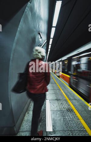 femme sur la plate-forme de la station de métro avec train de passage Banque D'Images