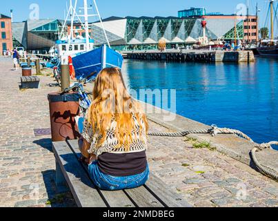 ELSINORE, DANEMARK – 3 AOÛT 2018 : une jeune fille lisant par Elsinore Harbour, Danemark. Banque D'Images