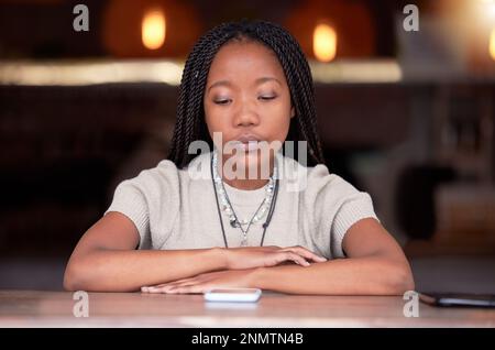 Dépression, triste et femme avec téléphone dans le café au cours de la rupture ou de la lutte sur son téléphone cellulaire. Déprimé, moody et malheureux femme africaine avec mental Banque D'Images