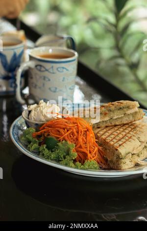 Plan vertical d'une assiette de panini végétalien avec salade de carottes et café pour le petit déjeuner Banque D'Images