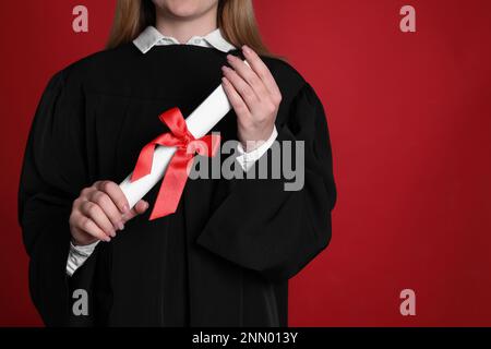 Étudiant avec diplôme sur fond rouge, gros plan Banque D'Images