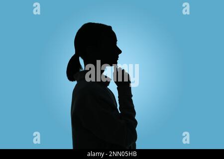 Silhouette de femme anonyme sur fond bleu clair Banque D'Images