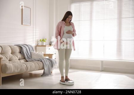 Femme enceinte debout sur des échelles à la maison Banque D'Images