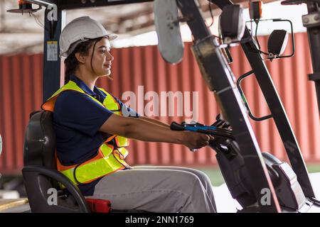 Femme indienne travailleur travail chauffeur de chariot élévateur à la cour de conteneur de l'entrepôt de fret de port pour l'industrie logistique sourire heureux Banque D'Images
