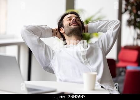 homme de bureau souriant ou homme d'affaires se détendant à la réception devant un ordinateur portable. Concept de bonheur au travail et de sérénité Banque D'Images