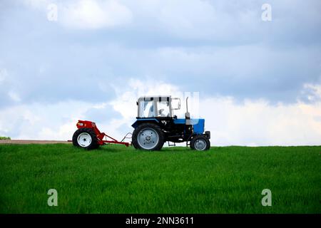 QUARTIER TELENESTI, MOLDOVA - MAI 2019: Tracteur à roues conducteur fertilisant le blé d'hiver avec des engrais minéraux. Alimentation des céréales. Rural la Banque D'Images