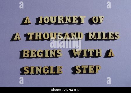 Un voyage de mille miles commence par un pas unique, des mots de motivation en lettres de l'alphabet de bois isolées sur le fond Banque D'Images