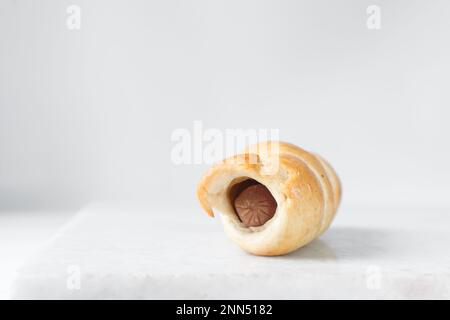 Un rouleau de saucisse sur un plateau en marbre, un rouleau de saucisse torsadé sur un plateau en marbre, de grands cochons dans une couverture en-cas Banque D'Images