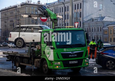 Moscou, Russie. 23rd février 2023. Les employés de la compagnie de stationnement de Moscou et l'inspecteur MADI évacuent une voiture mal garée de la chaussée du Garden Ring à Moscou, en Russie Banque D'Images