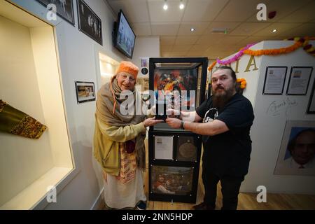 Le propriétaire du musée Roag Best est accompagné par les adeptes de Hare Krishna avec un pendentif appartenant à George Harrison exposé samedi au musée des Beatles de Liverpool, à l'occasion de ce qui aurait été l'anniversaire de 80th du guitariste et compositeur. Harrison, qui mourut en 2001 à l'âge de 58 ans, fit don du Bhaktivedanta Manor à Watford à la Société internationale pour la conscience Krishna (ISKCON), connue sous le nom de Hare Krishnas, en 1970s. Date de la photo: Samedi 25 février 2023. Banque D'Images