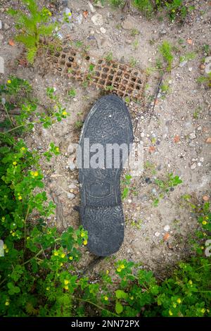 L'ancienne semelle de chaussure en caoutchouc noir repose sur le sol. Concept d'écologie. Banque D'Images