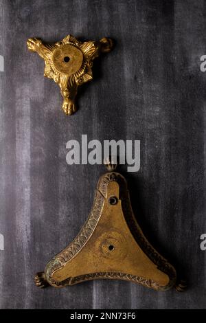 Deux anciennes bases de lampes électriques en laiton forgé ornées sur fond noir. Banque D'Images