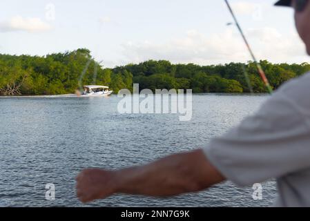 Valentica, Bahia, Brésil - 09 septembre 2022 : bateau naviguant sur la rivière una en fin d'après-midi tout en pêchant à la maison sur la rive. Ville de Valenca, Banque D'Images