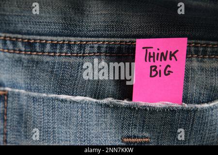 L'inscription de citations de motivation sur une étiquette dans une poche de jeans bleus. Pensez grand. Banque D'Images