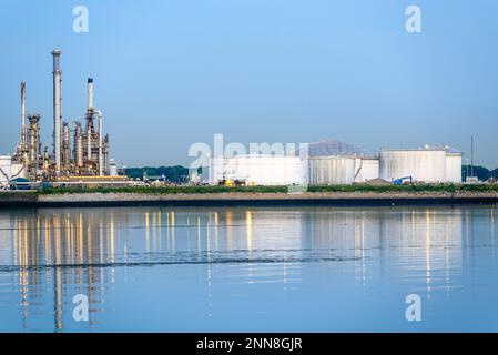 Réservoirs et tours de distillation dans une raffinerie de pétrole sur un port au crépuscule Banque D'Images