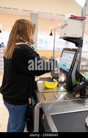 Jeune femme cashopper vue arrière payer pour la nourriture shopping debout au comptoir libre-service de caisse jusqu'au supermarché Morrisons février 2023 Royaume-Uni Banque D'Images