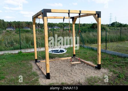 Un terrain de jeu moderne en forme de cube, en bois et en métal, debout dans la cour derrière la maison. Banque D'Images