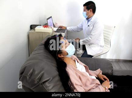 Femme latine et médecin avec masque de protection dans les examens médicaux effectuant l'électroencéphalogramme et la cartographie du cerveau en temps de contingence Covid-19 Banque D'Images