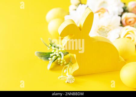 Composition de Pâques avec œufs colorés, lapin en bois et fleurs de printemps sur fond jaune. Copier l'espace. Banque D'Images