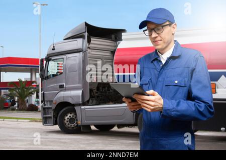 Homme avec une tablette numérique sur un fond de camion à essence avec remorque-citerne et une station-service Banque D'Images