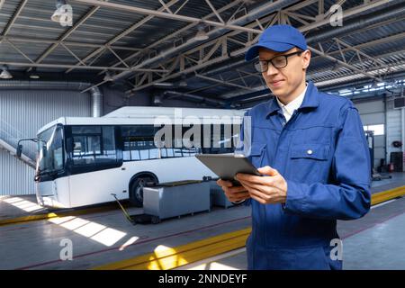 Chef de service avec tablette numérique sur l'arrière-plan du bus dans le garage Banque D'Images