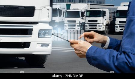 Manager avec une tablette numérique à côté des camions. Gestion de parc Banque D'Images