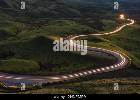 Route rurale sinueuse et sinueuse avec sentier léger depuis les phares menant à la campagne britannique. Banque D'Images