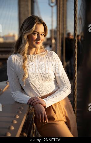 Un cliché vertical d'une jeune femme blonde vêtue de vêtements décontractés sur le pont de Brooklyn dans la ville de New York Banque D'Images