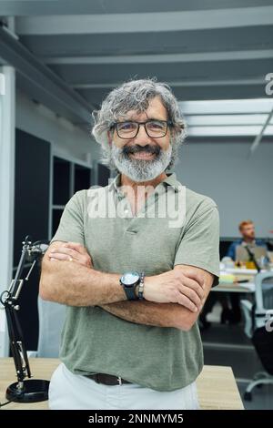 Photo verticale d'un homme d'affaires mûr souriant regardant une caméra debout au bureau lors d'une réunion du conseil d'équipe Banque D'Images
