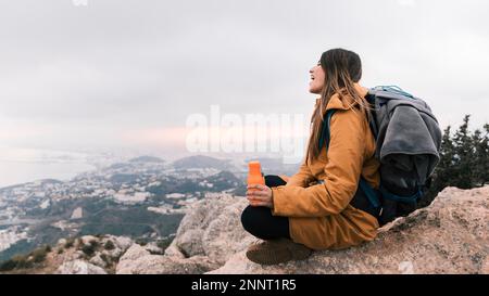 femme randonneur assis au sommet de la montagne tenant une bouteille d'eau main donnant sur la vue Banque D'Images