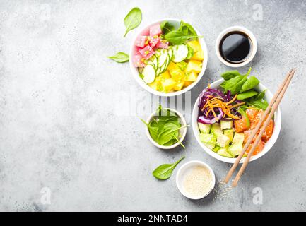 Deux poke-bols assortis avec poisson et légumes crus, espace pour le texte. Vue de dessus. Plat hawaïen traditionnel, fond de pierre rustique. Propreté saine Banque D'Images