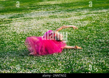 Ballerina faisant des fractionnements sur pelouse avec fleurs, parc de Battle point, île de Bainbridge, Washington, États-Unis Banque D'Images