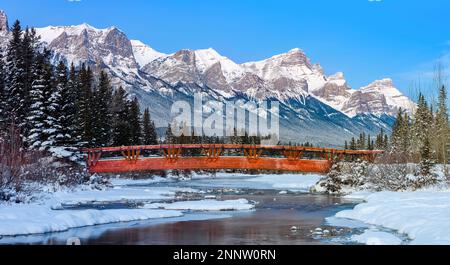 Passerelle au-dessus du ruisseau Polidemans dans un paysage de montagne enneigé avec Mount Rundle, Canmore, Alberta, Canada Banque D'Images