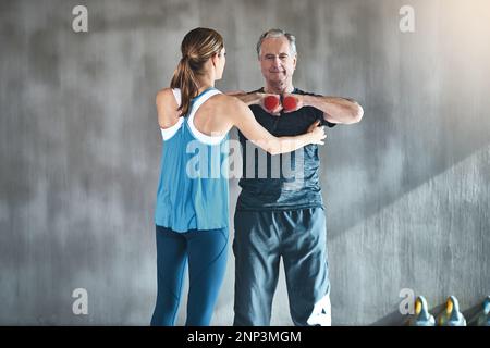 La thérapie physique aide à améliorer sa fonction musculaire et articulaire. un homme âgé utilisant des poids avec l'aide d'un thérapeute physique. Banque D'Images