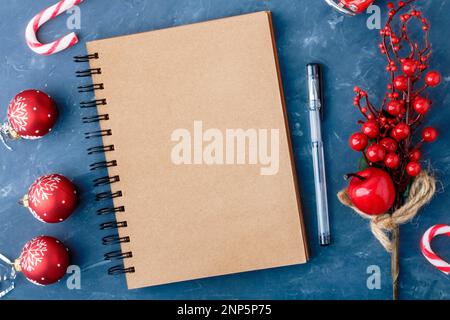 Bloc-notes pour les enregistrements.Une page vierge de bloc-notes sur un fond bleu à côté des branches de Noël et d'un ballon de Noël.Noël, concept du nouvel an.Haut v Banque D'Images