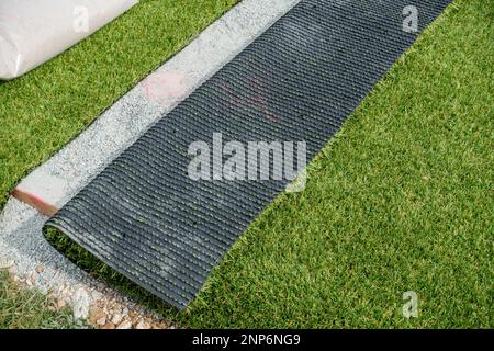 Gros plan sur un tapis d'herbe synthétique plié à l'arrière présentant une surface verte par tous les temps et également le dos noir, le terrain de sport Uppingham School. Banque D'Images