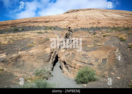 Touristes marchant vers le haut Ladera Del volcan Las Grietas Lanzarote, îles Canaries, Espagne formations rocheuses volcaniques causées par l'érosion avec vue sur montana bla Banque D'Images