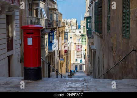 Une ancienne boîte postale rouge vue au-dessus d'une rue escarpée de la Valette à Malte. Banque D'Images