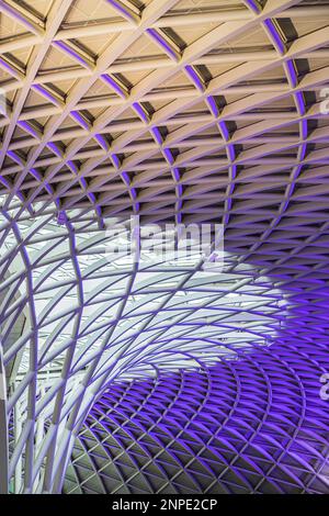 Un gros plan du plafond abstrait au-dessus de la gare de Kings Cross illuminé dans des lumières violettes. Banque D'Images