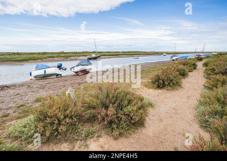 Des bateaux amarrés sur le côté de Blakeney, sur la côte nord de Norfolk. Banque D'Images