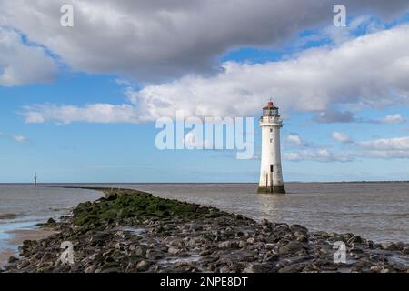 Perch Rock Lighthouse à côté des défenses marines en courbure qui jailèrent dans la baie de Liverpool. Banque D'Images