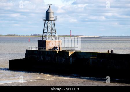 Wilhelmshaven, Allemagne. 26th févr. 2023. Les randonneurs sont dans le temps ensoleillé sur la jetée en face de la croix historique le long de la baie de Jade. En arrière-plan le feu arrière Preußeneck près d'Eckwarderhörne peut être vu. Credit: Hauke-Christian Dittrich/dpa/Alay Live News Banque D'Images